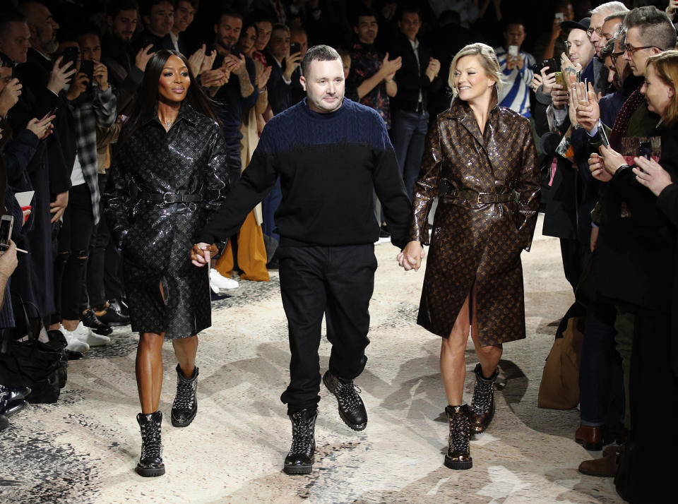 FILE - In this Jan.18 2018 file photo, designer Kim Jones, center, is escorted by models Kate Moss, right, and Naomi Campbell after presenting his Louis Vuitton men's Fall-Winter 2018/2019 collection in Paris. The Council of Fashion Designers of America (CFDA) announced Jones as International Men's Designer of the Year for the 2020 CFDA Fashion Awards. (AP Photo/Francois Mori, File)