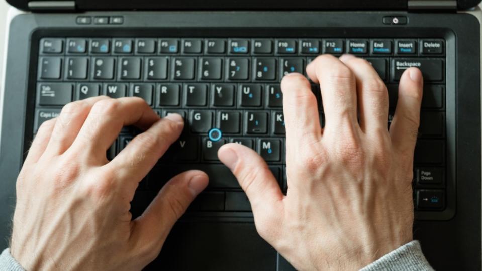 Two hands type on a keyboard.