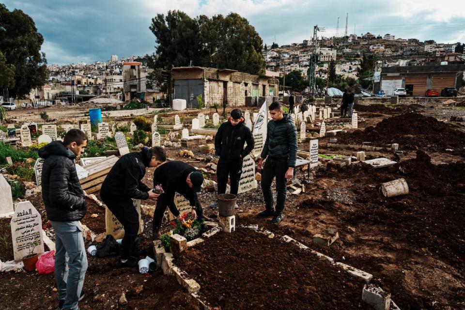 People visit and pay respects at a gravesite.