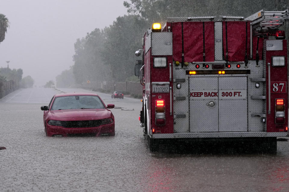 Un camión de bomberos se echa en reversa después de que un automovilista quedó varado en una inundación por las lluvias torrenciales que trajo la tormenta tropical Hilary, el domingo 20 de agosto de 2023, en Palm Desert, California. (AP Foto/Mark J. Terrill)