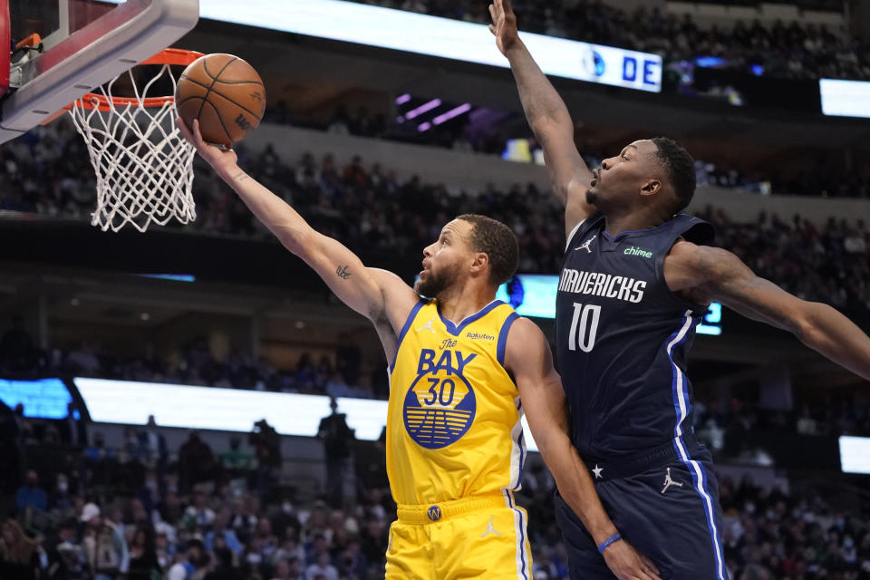 Golden State Warriors guard Stephen Curry (30) goes in for a lay-up again Dallas Mavericks forward Dorian Finney-Smith (10) during the second half of an NBA basketball game in Dallas, Wednesday, Jan. 5, 2022. (AP Photo/LM Otero)