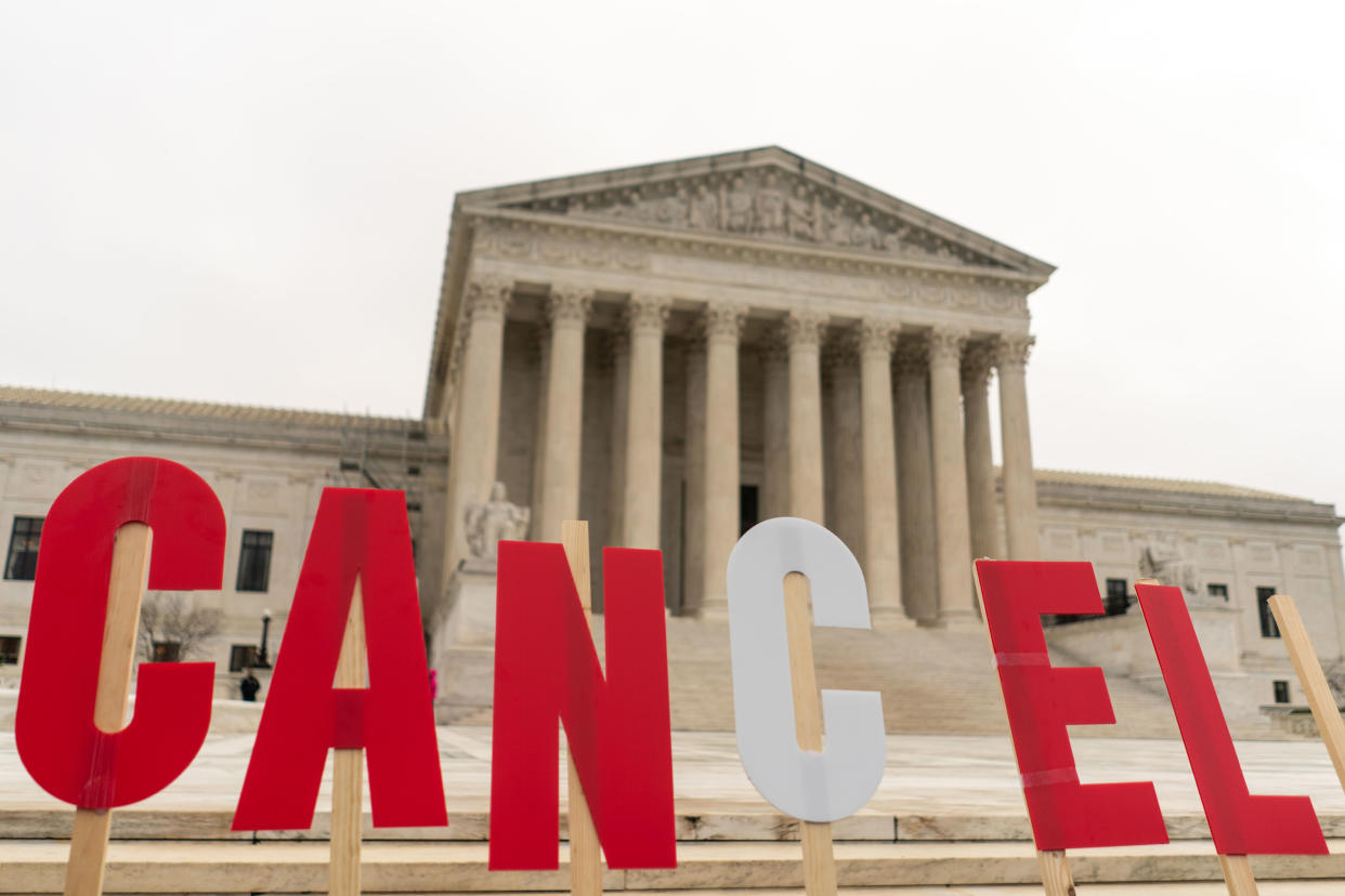 On the steps in front of the Supreme Court, supporters of student debt relief hold up cutout letters spelling: Cancel.