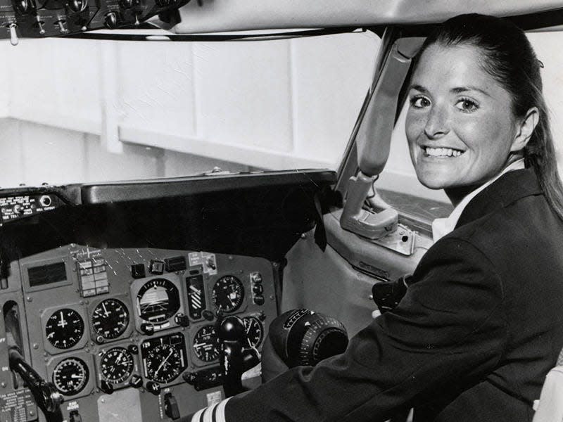 Bonnie Tiburzi, the first woman to fly as a pilot for American Airlines, posing for a picture in the cockpit of a plane.