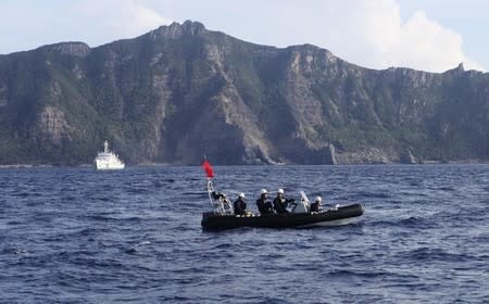 A Japan Coast Guard boat (front) and vessel sail as Uotsuri island, one of the disputed islands, called Senkaku in Japan and Diaoyu in China, is pictured in the background, in the East China Sea August 18, 2013. REUTERS/Ruairidh Villar