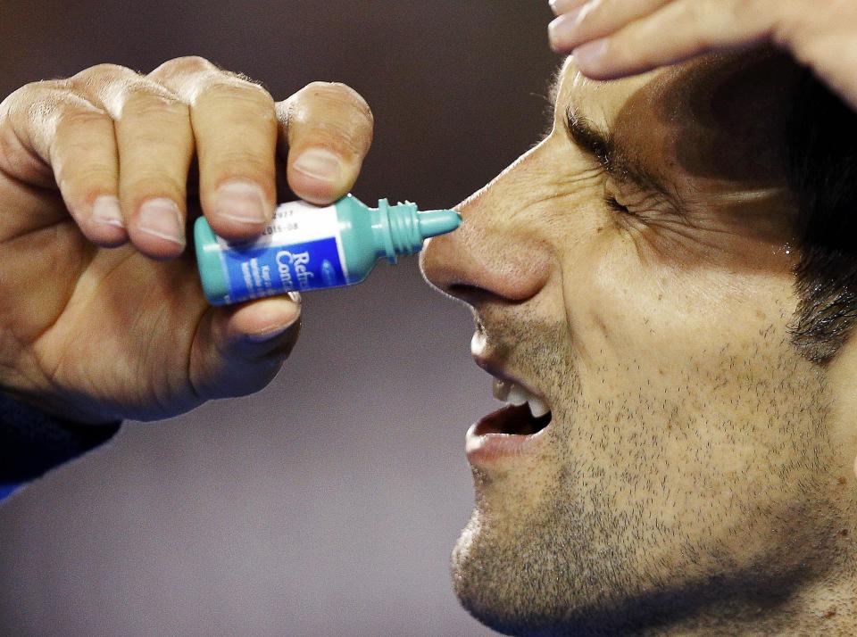 Novak Djokovic of Serbia applies eye drops during his men's singles semi-final match against Stan Wawrinka of Switzerland at the Australian Open 2015 tennis tournament in Melbourne January 30, 2015. REUTERS/Athit Perawongmetha (AUSTRALIA - Tags: SPORT TENNIS)