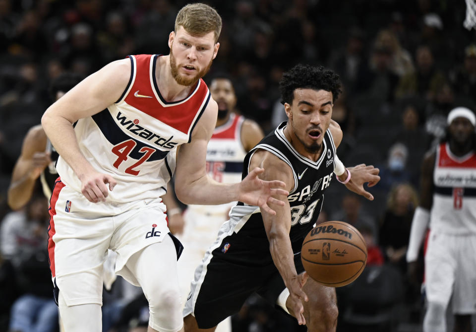 San Antonio Spurs' Tre Jones (33) and Washington Wizards' Davis Bertans (42) chase the ball during the first half of an NBA basketball game, Monday, Nov. 29, 2021, in San Antonio. (AP Photo/Darren Abate)