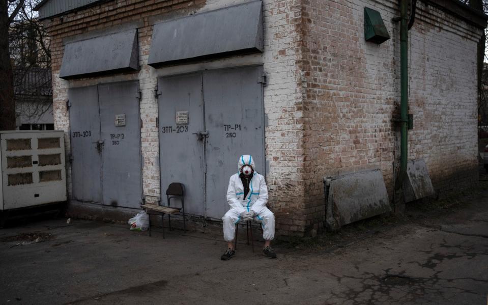 A forensics worker rests after loading bodies onto a truck in Bucha - AP