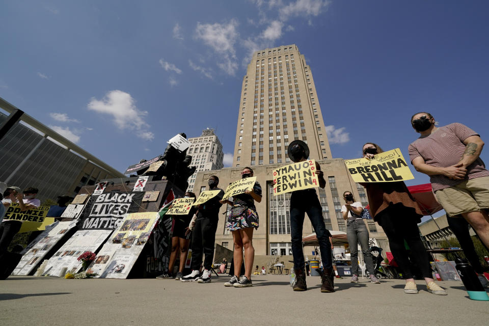 Protesters hold signs outside city hall Thursday, Oct. 8, 2020, in Kansas City, Mo., demanding the resignation of an officer who knelt on the back of nine-months-pregnant Black woman, Deja Stallings, while arresting her the previous week, and Police Chief Rick Smith. (AP Photo/Charlie Riedel)