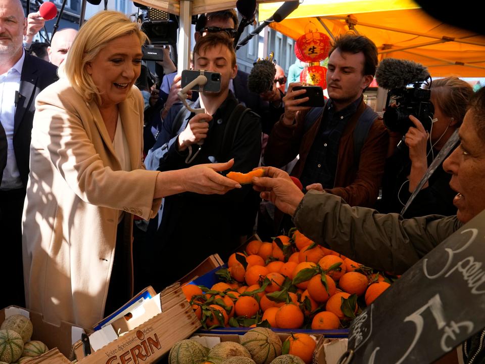 French far-right leader and presidential candidate Marine Le Pen tastes a melon coming from Morocco as she campaigns at a street market (AP)