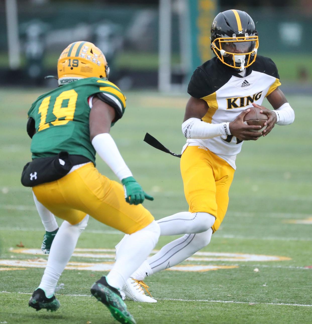 Detroit King quarterback Darryl Flemister III runs by Grosse Pointe North defender King Jackson at Grosse Pointe North High School on Friday, Nov. 3, 2023.