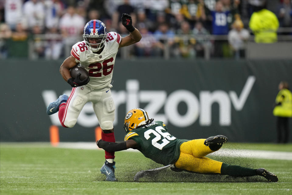 New York Giants running back Saquon Barkley (26) breaks away from Green Bay Packers safety Darnell Savage (26) for a touchdown during the second half of an NFL football game at the Tottenham Hotspur stadium in London, Sunday, Oct. 9, 2022. (AP Photo/Alastair Grant)