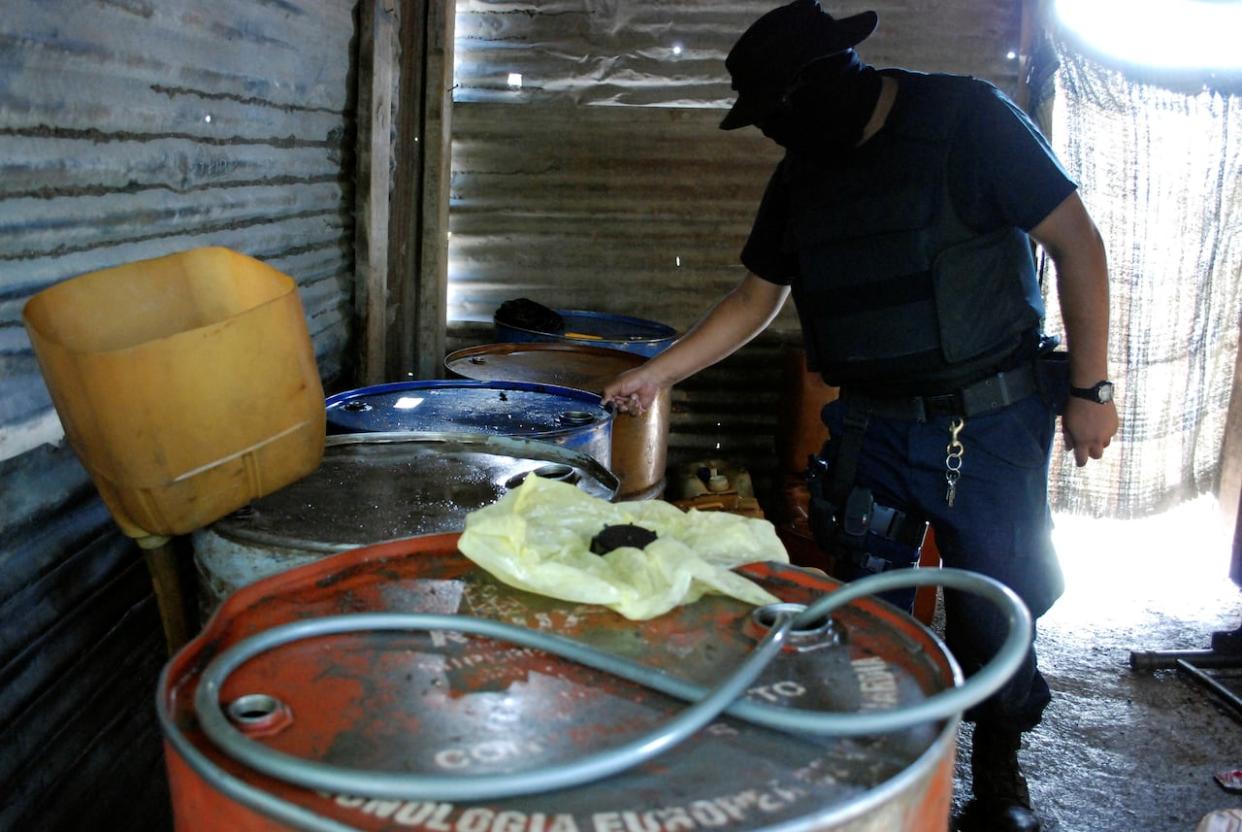 In this 2011 file photo, a Mexican police officer inspects barrels containing stolen diesel fuel in the municipality of Apodaca. A B.C. judge has ruled to extradite the former head of security for Mexico's state oil monopoly Pemex due to his alleged role in covering up gas theft. (Josue Gonzalez/Reuters - image credit)