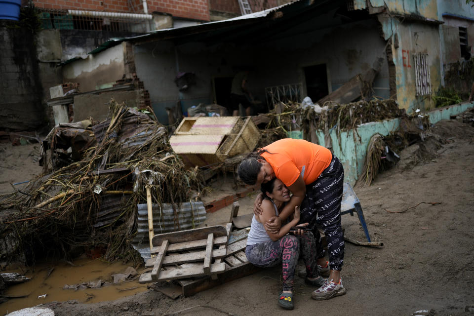 A neighbor, right, comforts a woman crying in front of her damaged home by flooding in Las Tejerias, Venezuela, Sunday, Oct. 9, 2022, after days of heavy rains caused the overflow of a river. (AP Photo/Matias Delacroix)