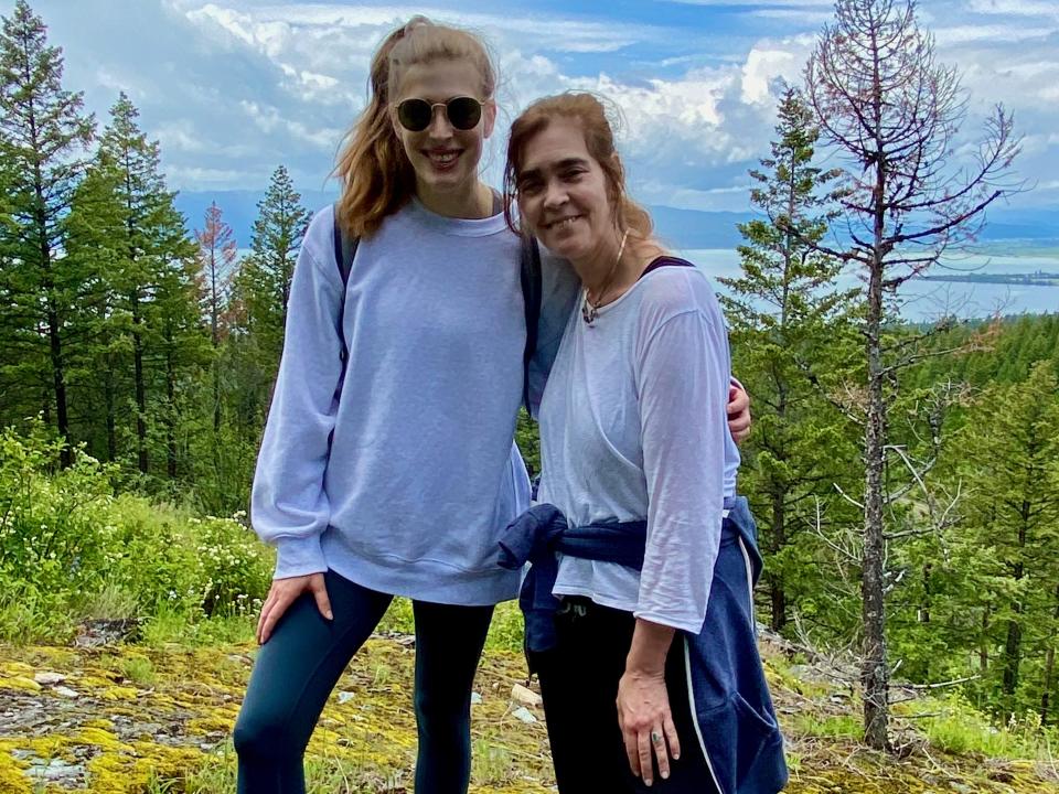 A mother and her daughter posing for a picture while hiking in the woods.