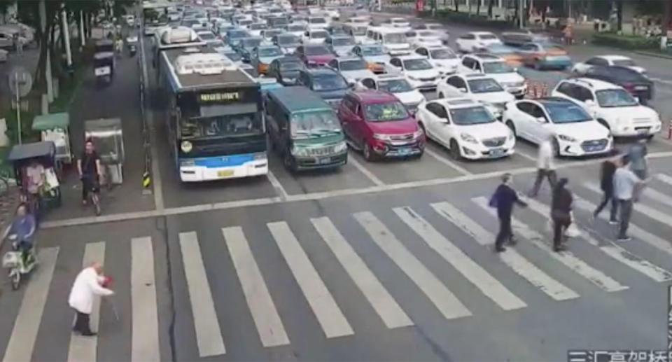 The senior citizen, with two walking sticks in hand, appears to struggle while shuffling across a zebra crossing. Source: Weibo / Mianyang Police