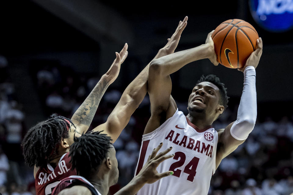FILE - Alabama forward Brandon Miller (24) fires off a shot with Arkansas guard Nick Smith Jr. (3) and guard Davonte Davis (4) defending during the second half of an NCAA college basketball game, Saturday, Feb. 25, 2023, in Tuscaloosa, Ala. Miller was selected to the Associated Press All-America first team in results released Tuesday, March 14, 2023. (AP Photo/Vasha Hunt, File)