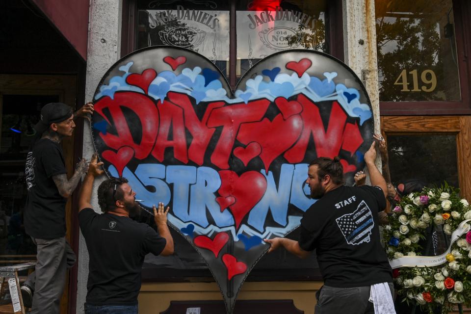 DAYTON, OH - AUGUST 6: Metal fabricator Nick Bruno, Kyle Knox, James Bunn, and Jason Phillips hang a metal-fabricated "Dayton Strong" sign on the front of Ned Pepper's Bar at the site where Dayton mass shooting gunman Connor Betts was gunned down by policer in the city's historic Oregon District on Tuesday, August 6, 2019, in Dayton, OH. The mass shooting attack came less than a day after a man with a high-powered weapon killed 20 people in El Paso, Texas, and a week after a gunman killed three people and wounded 12 at the Gilroy Garlic Festival in California. (Photo by Jahi Chikwendiu/The Washington Post via Getty Images).