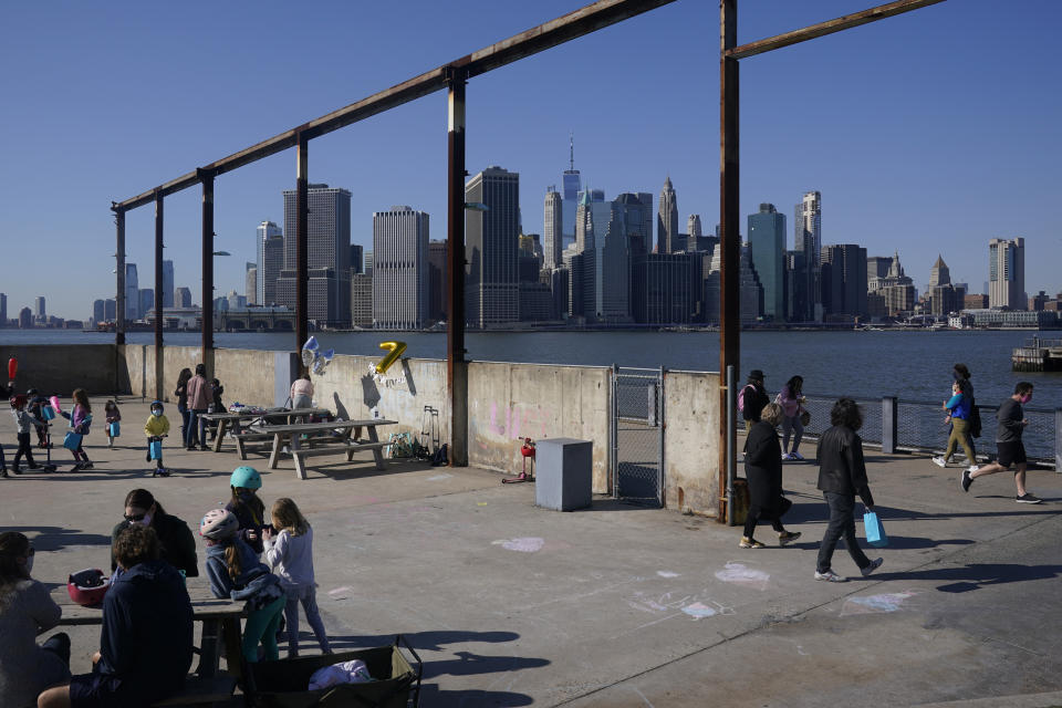 FILE - In this March 21, 2021, file photo people enjoy the sunny weather and a view of the Manhattan skyline from the Brooklyn waterfront in New York. The surge in the nation’s urban population could give these urban centers greater influence in reshaping the balance of power in Washington as congressional redistricting gets under way. New York in particular is giving Democrats hope. The most populous city in the United States added some 629,000 new residents. (AP Photo/Seth Wenig, File)