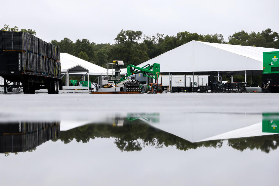 Workers disassemble hangar-sized tents, Tuesday, Oct. 4, 2022, in the parking lot of Orchard Beach in the Bronx borough of New York. Giant tents for temporarily housing migrants arriving in New York City are being moved to an island off Manhattan from a remote corner of the Bronx, after storms raised concerns over flooding at the original site. (AP Photo/Julia Nikhinson)