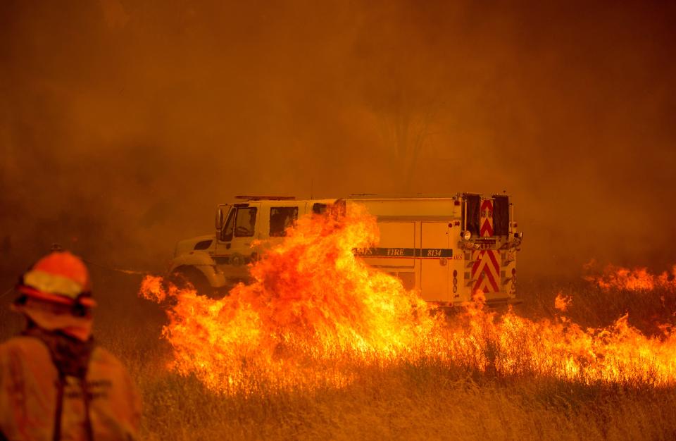 <p>A fire vehicle is surrounded by flames as the Pawnee fire jumps across highway 20 near Clearlake Oaks, Calif. on July 1, 2018. (Photo: Josh Edelson/AFP/Getty Images) </p>