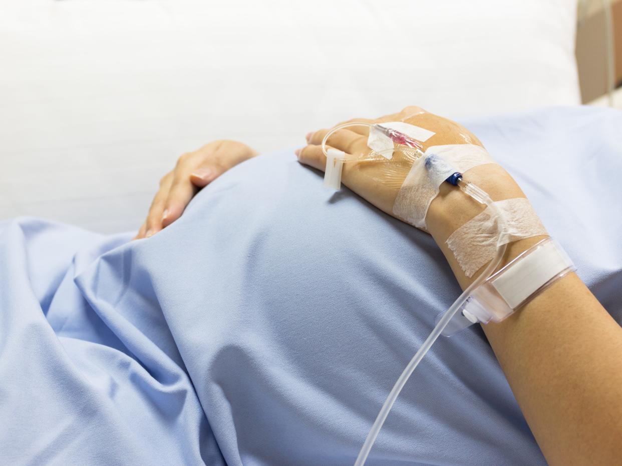 Pregnant Woman patient is on drip receiving a saline solution on bed VIP room at hospital