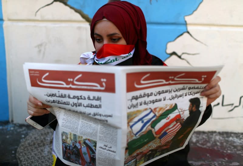 An Iraqi demonstrator reads Tuktuk newspaper during the ongoing anti-government protests, in Baghdad