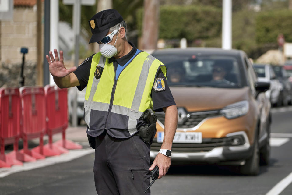 A police officer controls the road to the H10 Costa Adeje Palace hotel in Tenerife, Canary Island, Spain, Tuesday, Feb. 25, 2020. Spanish officials say a tourist hotel on the Canary Islands has been placed in quarantine after an Italian doctor staying there tested positive for the new coronavirus. (AP Photo)