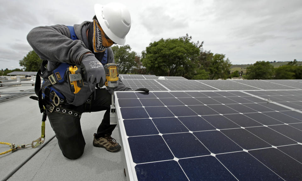 FILE - Gen Nashimoto, of Luminalt, installs solar panels in Hayward, Calif., on April 29, 2020. California air regulators are set to approve an ambitious plan for the state to achieve carbon neutrality by 2045. Doing so will require a rapid transition away from oil and gas and toward renewable energy to power everything from cars to buildings. (AP Photo/Ben Margot, File)