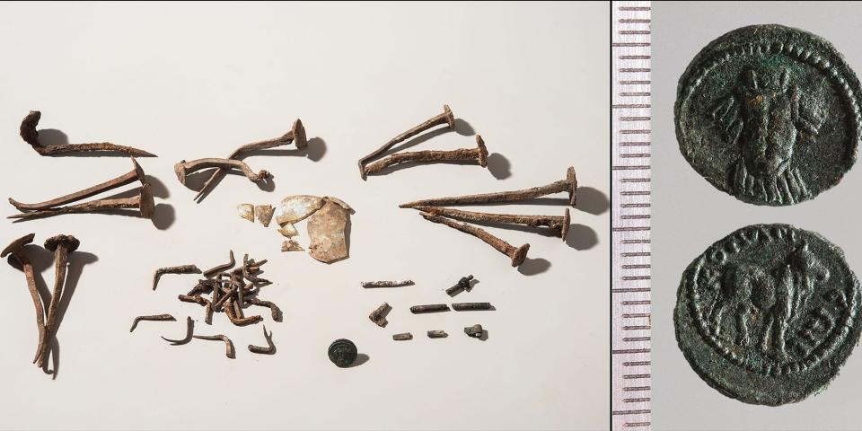 Nails of different shapes are laid out on a white background. Some are bent or twisted, suggesting they were imbued with "magical properties". Next to the nails are Roman coins.