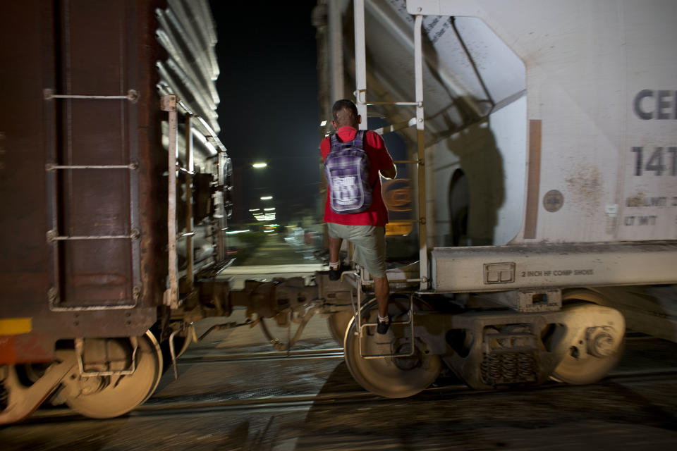 A Central American migrant jumps on a northbound freight train as it pulls out of the station in Arriaga, Mexico. (AP Photo/Rebecca Blackwell)