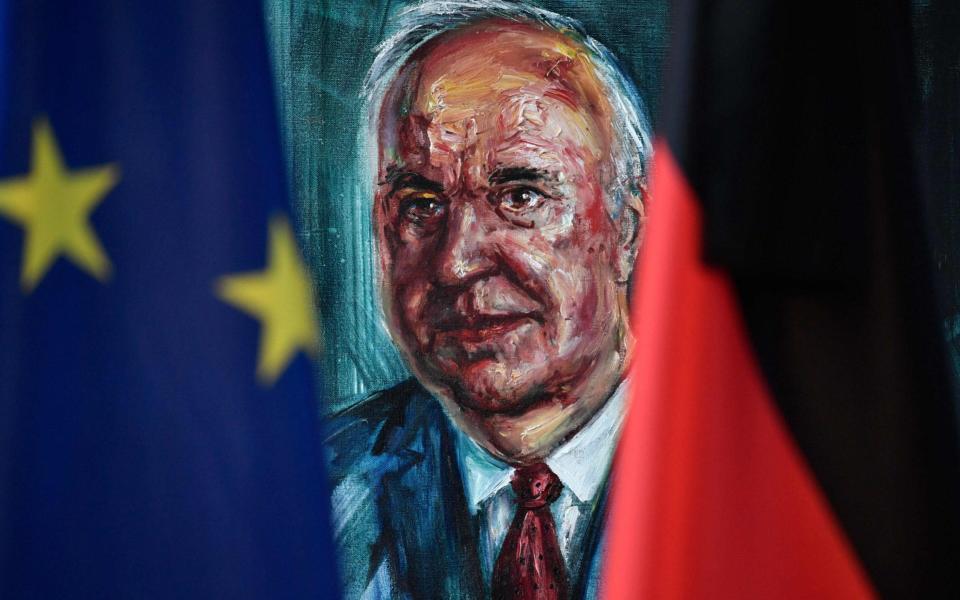 A European (L) and a German flag frame the official portrait of former German Chancellor Helmut Kohl on display at the Chancellery in Berlin on June 18, 2017 - AFP