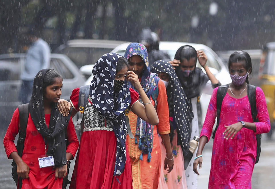 People walk in the rain in Hyderabad, India, Saturday, Nov. 20, 2021. More than a dozen people have died and dozens are reported missing in the southern Indian state of Andhra Pradesh after days of heavy rains, authorities said. (AP Photo/Mahesh Kumar A.)