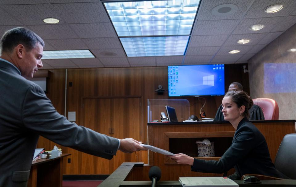 Assistant Oakland County Prosecutor Marc Keast, left, hands a report to forensic psychiatrist Dr. Lisa Anacker as Ethan Crumbley appears in the Oakland County Courtroom of Kwame Rowe, on Friday, Aug. 18, 2023, in Pontiac, Mich. The Oakland County Prosecutors are making their case that Crumbley, a teenager, should be sentenced to life without parole for killing four students at Oxford High School in 2021.