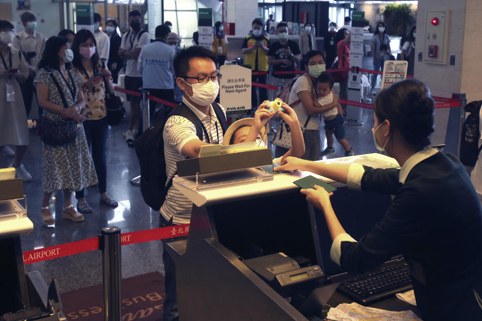 Participants check in during a mock trip abroad at Taipei Songshan Airport in Taipei, Taiwan, Tuesday, July 7, 2020. Dozens of would-be travelers acted as passengers in an activity organized by Taiwan’s Civil Aviation Administration to raise awareness of procedures to follow when passing through customs and boarding their plane at Taipei International Airport. (AP Photo/Chiang Ying-ying)