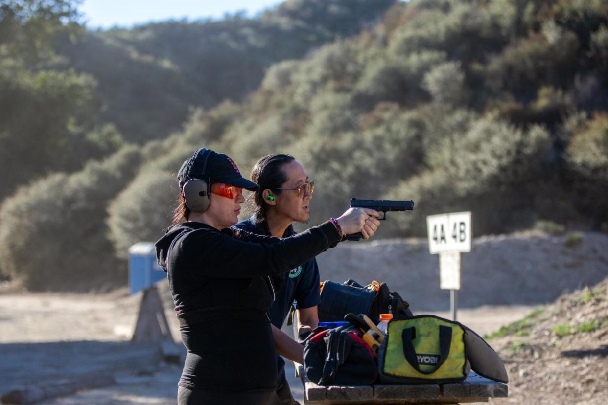 Nikki Shrieves, left, wears ear and eye protection while firing a handgun as instructor Tom Nguyen looks on by her side