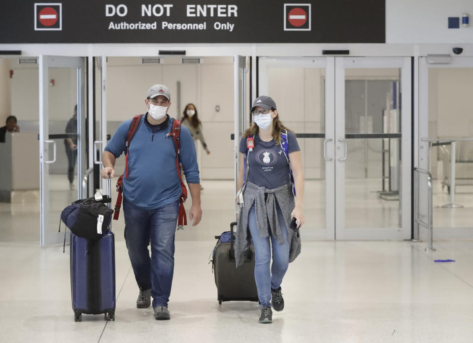 Mike Rustici, left, and Linda Scruggs exit customs after arriving on a flight from Lima, Peru, Saturday, March 21, 2020, at Miami International Airport in Miami. The pair's plight illustrates the desperation people stuck abroad experienced as the COVID-19 pandemic spread. Peru confirmed its first case of the virus on March 6. By the time Scruggs and Rustici arrived a week later, it was spreading. (AP Photo/Wilfredo Lee)