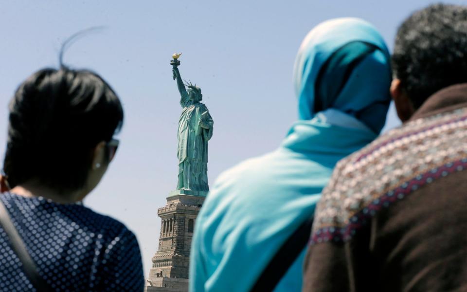 People look at the Statue of Liberty from a ferry boat in Jersey City - Credit: AP