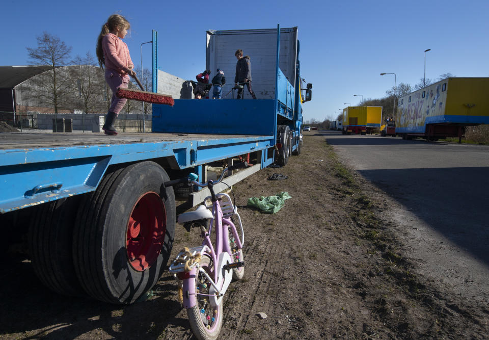 Children of the Renz Circus family play around the stranded trucks and animals in Drachten, northern Netherlands, Tuesday, March 31, 2020. The circus fleet of blue, red and yellow trucks have had a fresh lick of paint over the winter. But now, as coronavirus measures shut down the entertainment industry across Europe, they have no place to go. "It's catastrophic for everybody," said Sarina Renz, of the German family circus that has been in existence since 1842. (AP Photo/Peter Dejong)