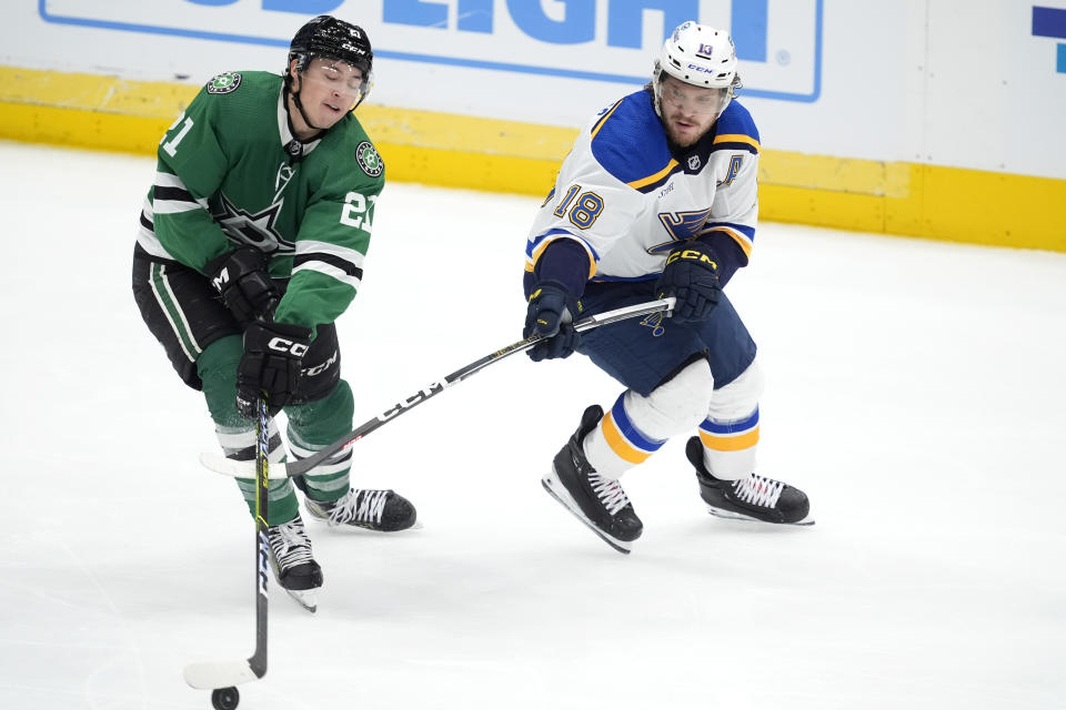 Dallas Stars left wing Jason Robertson (21) looks to take control of the puck in front of St. Louis Blues center Robert Thomas (18) in the third period of an NHL hockey game in Dallas, Wednesday, April 17, 2024. (AP Photo/Tony Gutierrez)