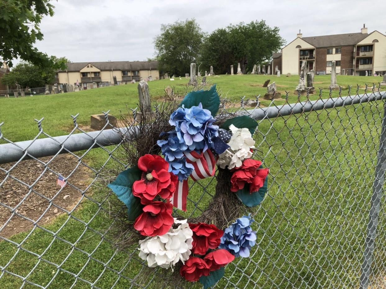 A wreath adorns the fence of the Seceder Cemetery in Reynoldsburg, where nearby apartments overlook 300 graves, including those of 12 U.S. veterans.