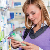 Woman reading information on a bottle of lotion.