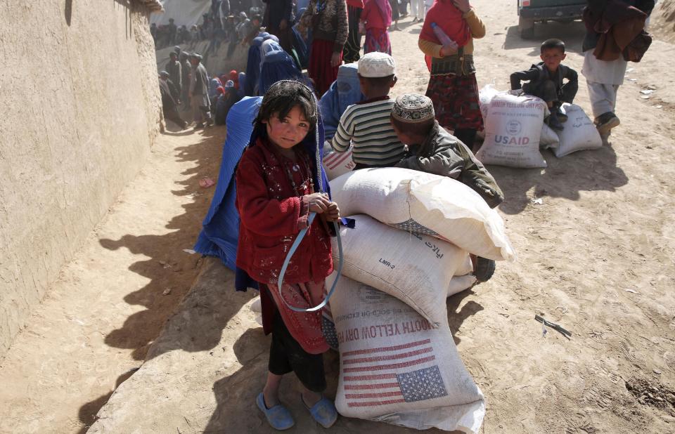 An Afghan girl stands near of food donations near the site of Friday's landslide that buried Abi-Barik village in Badakhshan province, northeastern Afghanistan, Tuesday, May 6, 2014. Authorities tried to help families displaced by the torrent of mud that swept through Abi-Barik village after hundreds were killed. (AP Photo/Massoud Hossaini)