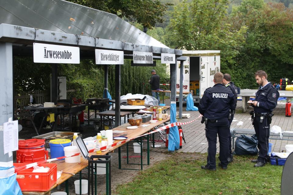 In this Sunday, Sept. 8, 2019 photo police officers investigate a booth after an explosion at a village festival in Freudenberg, Germany. Authorities say 14 people have been injured, five of them with life-threatening burns, during an explosion at a village festival in western Germany. Police told German news agency dpa that it appears likely that oil inside a big frying pan caused the explosion at the local 'Backesfest' (bakery festival) that was attended by about 100 people. (Berthold Stamm/dpa via AP)