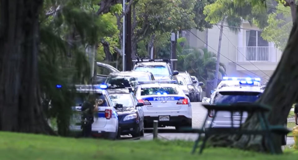 Police cars at the scene of Hawaii shooting where two officers were shot and homes on fire.