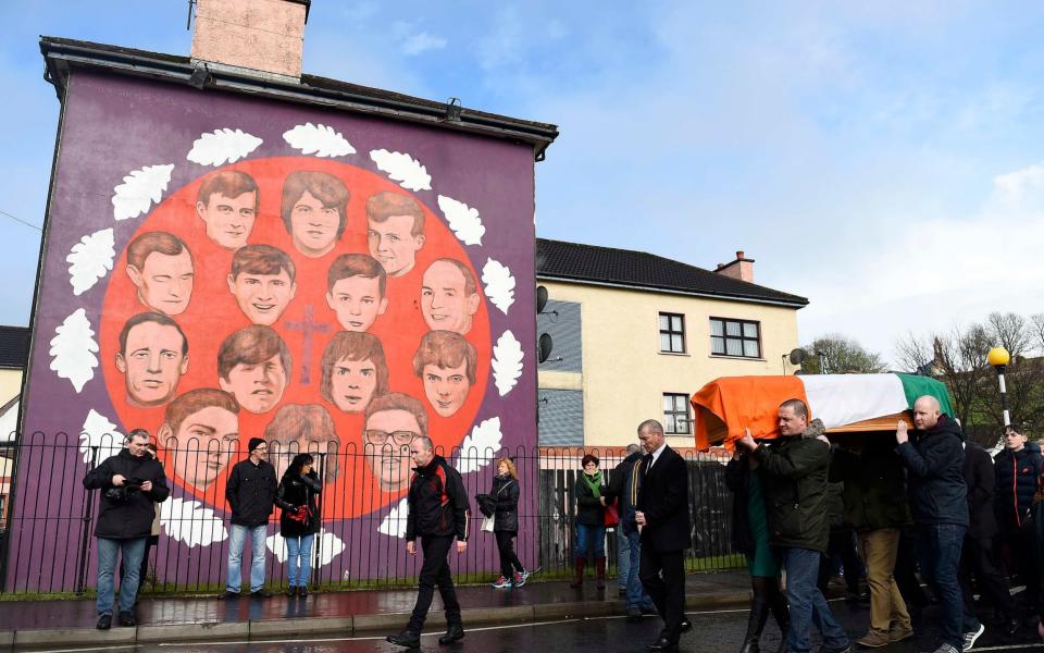 Mourners walk with pall bearers as they carry the coffin of Martin McGuinness through the streets of Londonderry, Northern Ireland - Credit: CLODAGH KILCOYNE /REUTERS 