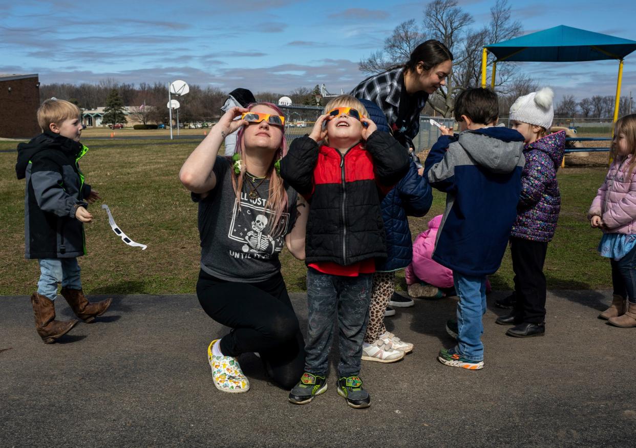 Abby Kruse, a Great Start Readiness Program aid, looks at the sun with her solar eclipse glasses alongside one of her students, Merlin Sorensen, during class at Mason Central Elementary School in Erie on March 7.
