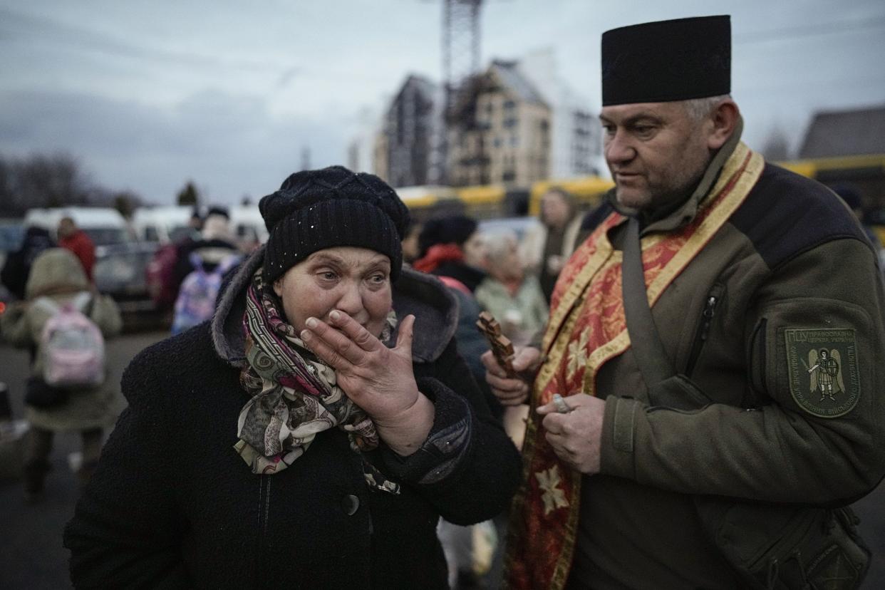 A military priest tries to comfort a crying woman who was evacuated from Irpin, at a triage point in Kyiv, Ukraine, Wednesday, March 9, 2022.