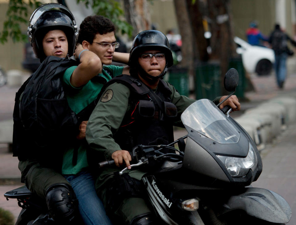 Guardias nacionales bolivarianos motorizados llevan detenido a un manifestante antigubernamental durante una protesta para demandar la libertad de estudiantes detenidos en Caracas, Venezuela, el lunes 12 de mayo de 2014.(AP Photo/Fernando Llano)