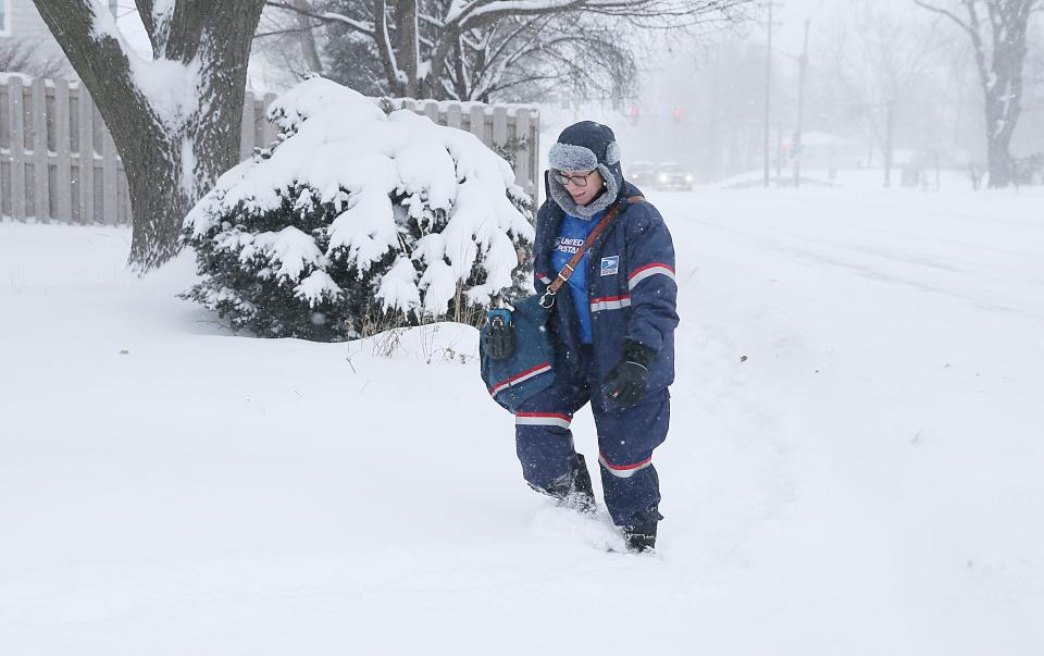Postal worker Jamisse Arocho walks in the snow to deliver mail during the winter storm on Grand Avenue on Friday, Jan. 12, 2024, in Ames, Iowa.