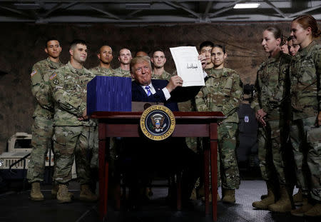 U.S. President Donald Trump holds up the National Defense Authorization Act after signing it in front of soldiers from the U.S. Army's 10th Mountain Division at Fort Drum, New York, U.S., August 13, 2018. REUTERS/Carlos Barria